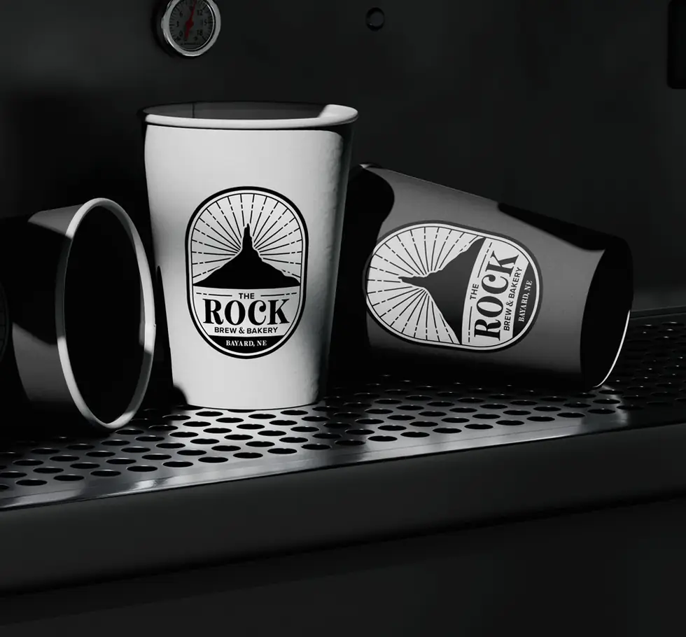 The Rock Brews and Bakery brand identity on coffee cups